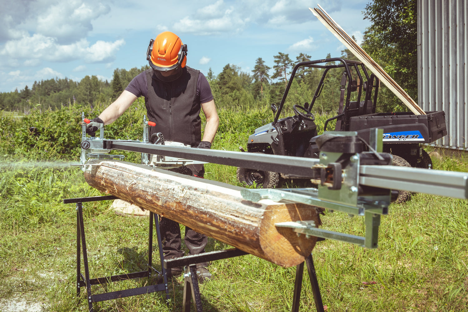 Person using ClampMill chainsaw mill to cut logs outdoors